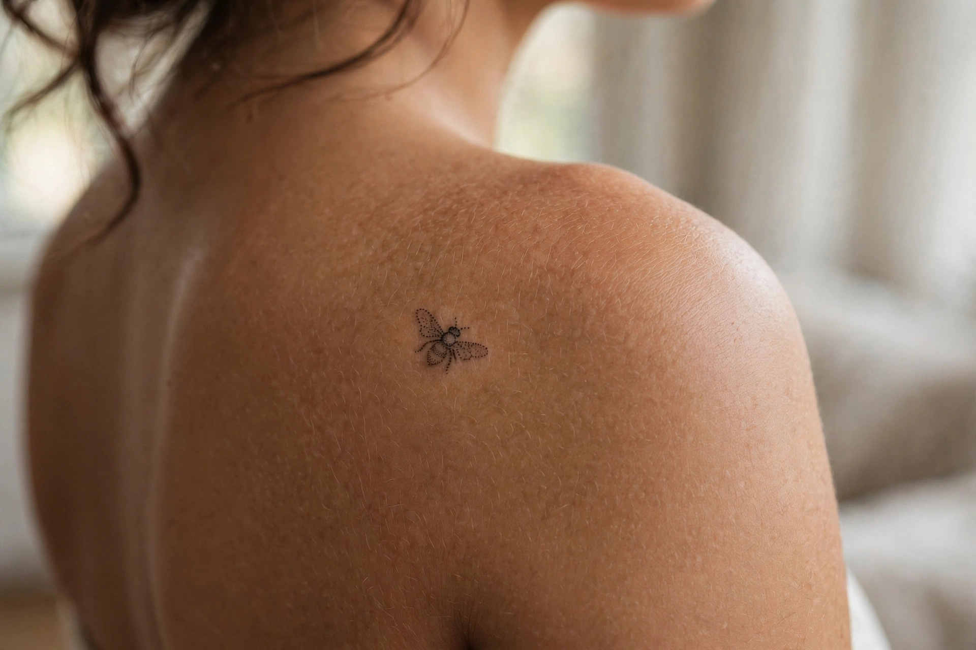 Minimalist tiny honeybee tattoo with delicate wings on a wrist