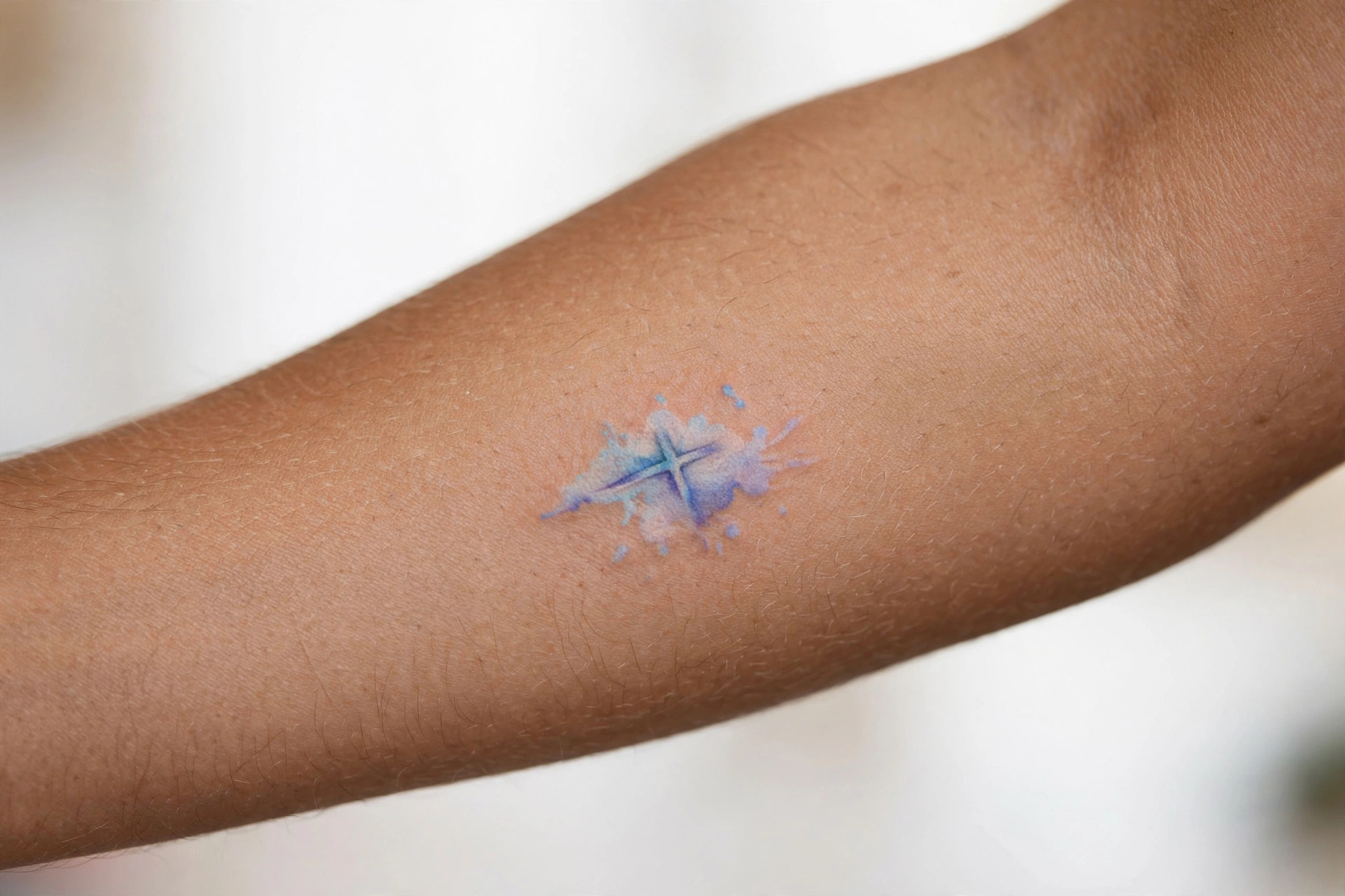 Tiny black cross tattoo on the side of a woman's finger