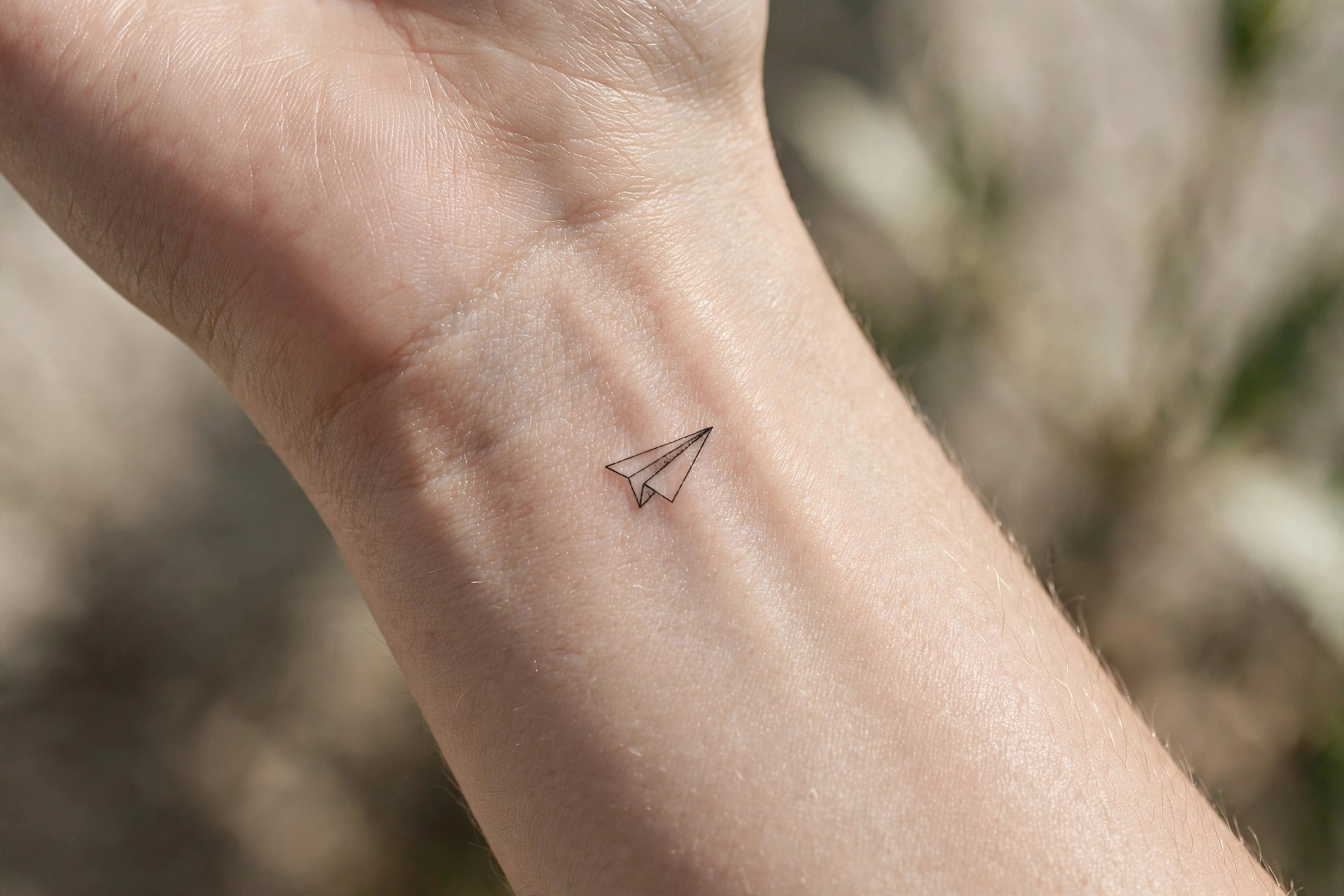 Tiny paper plane first tattoo idea for women on the wrist