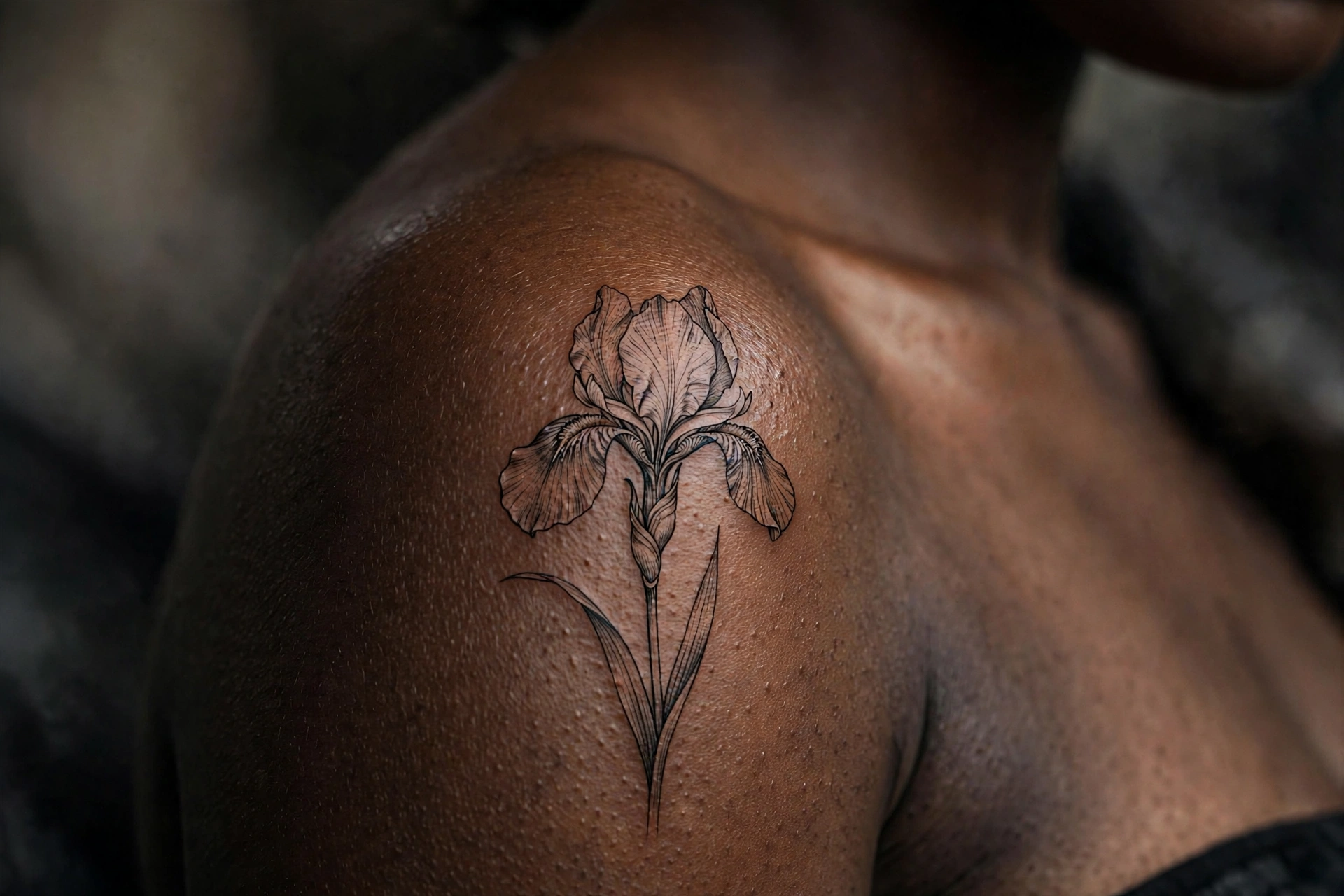 Fine-line iris flower tattoo with delicate purple-grey shading on a ribcage