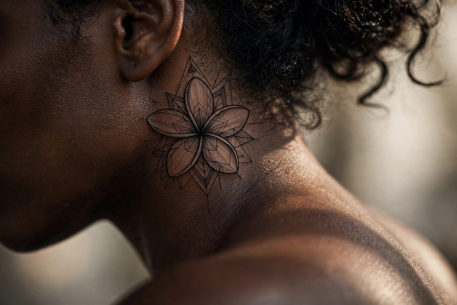 Small plumeria frangipani flower tattoo tucked behind a woman's ear