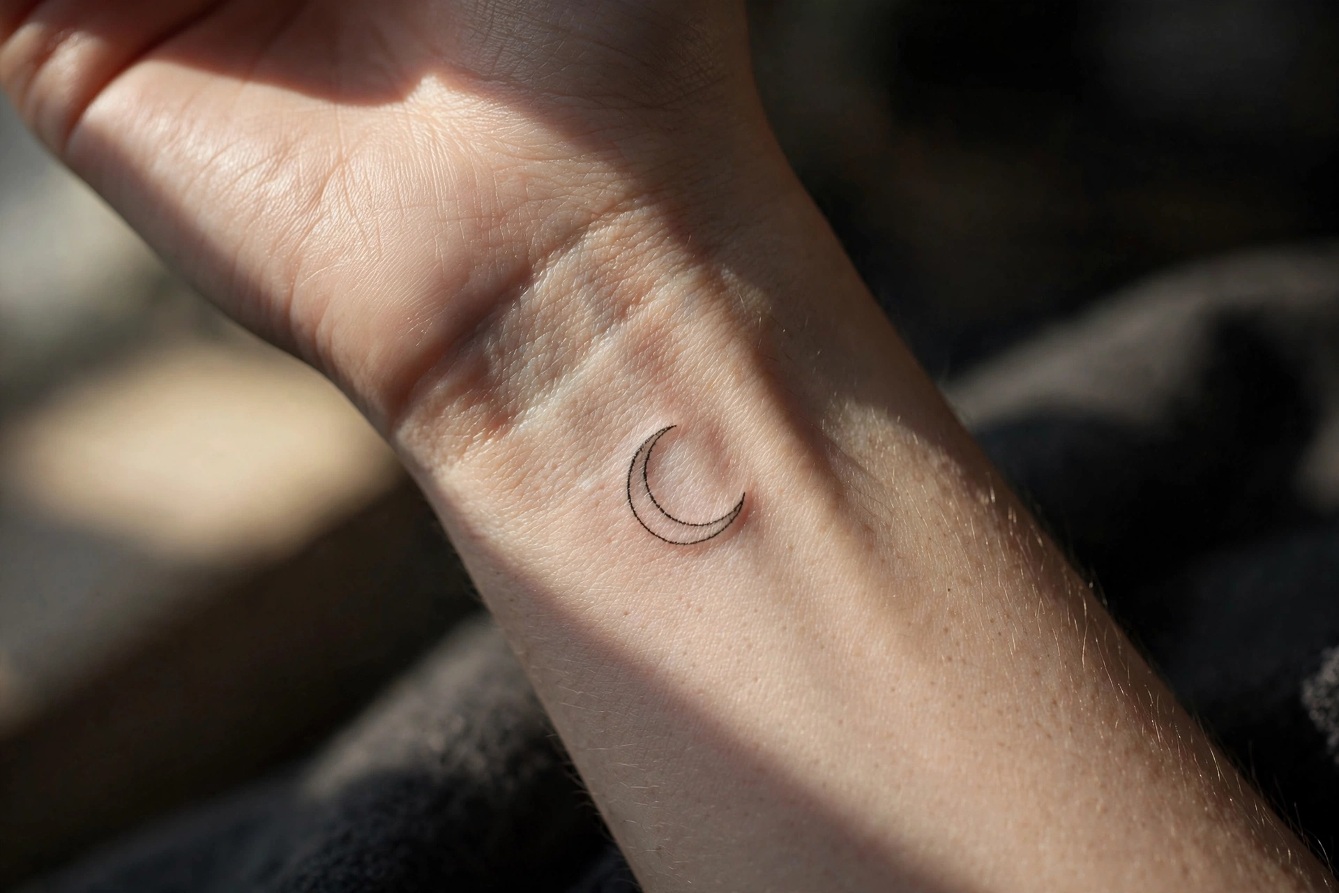 Minimalist crescent moon tattoo on inner wrist