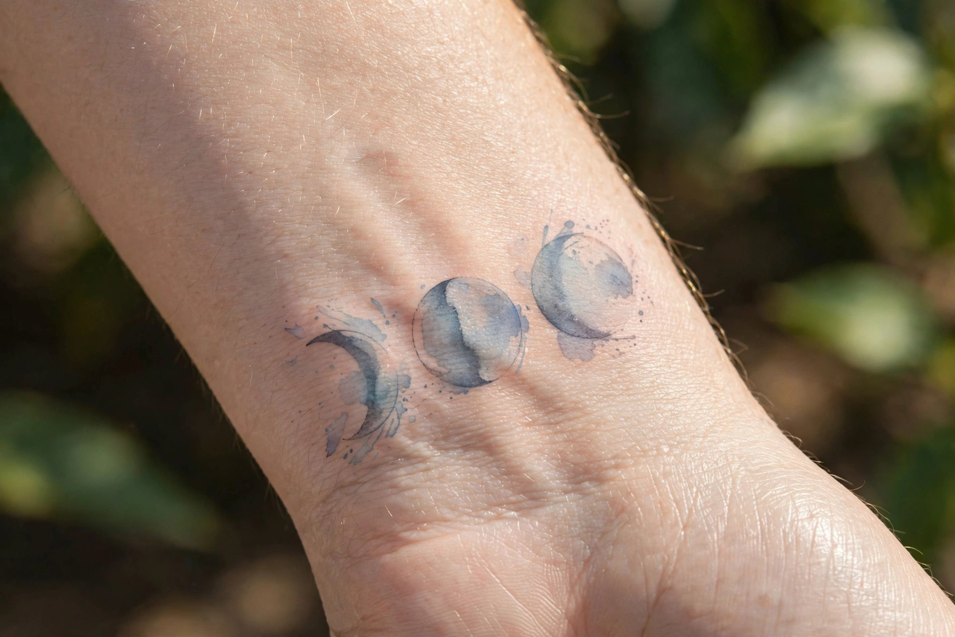 Three moon phases tattooed in a row on the inner wrist