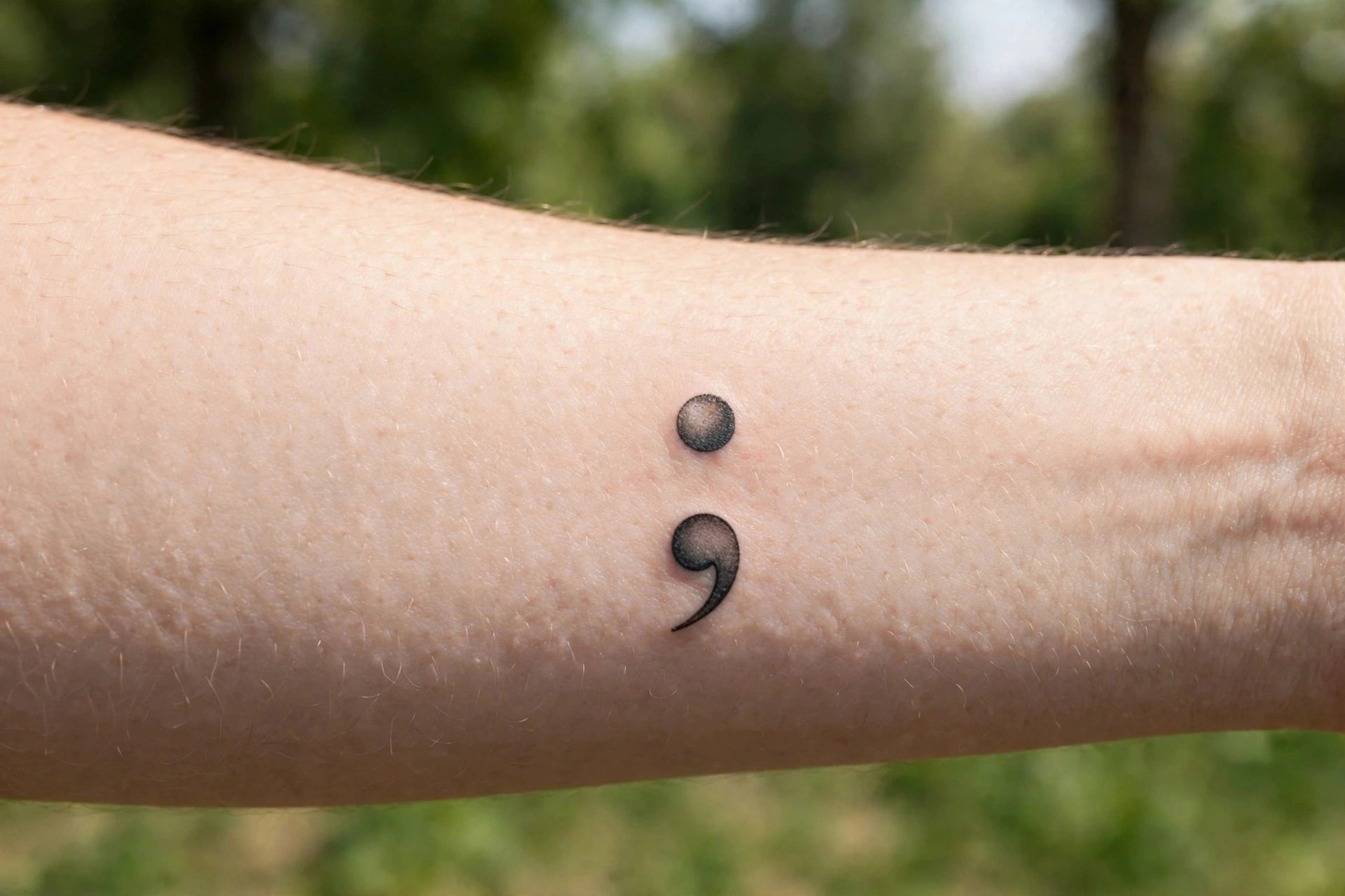 Small semicolon tattoo on a man's wrist