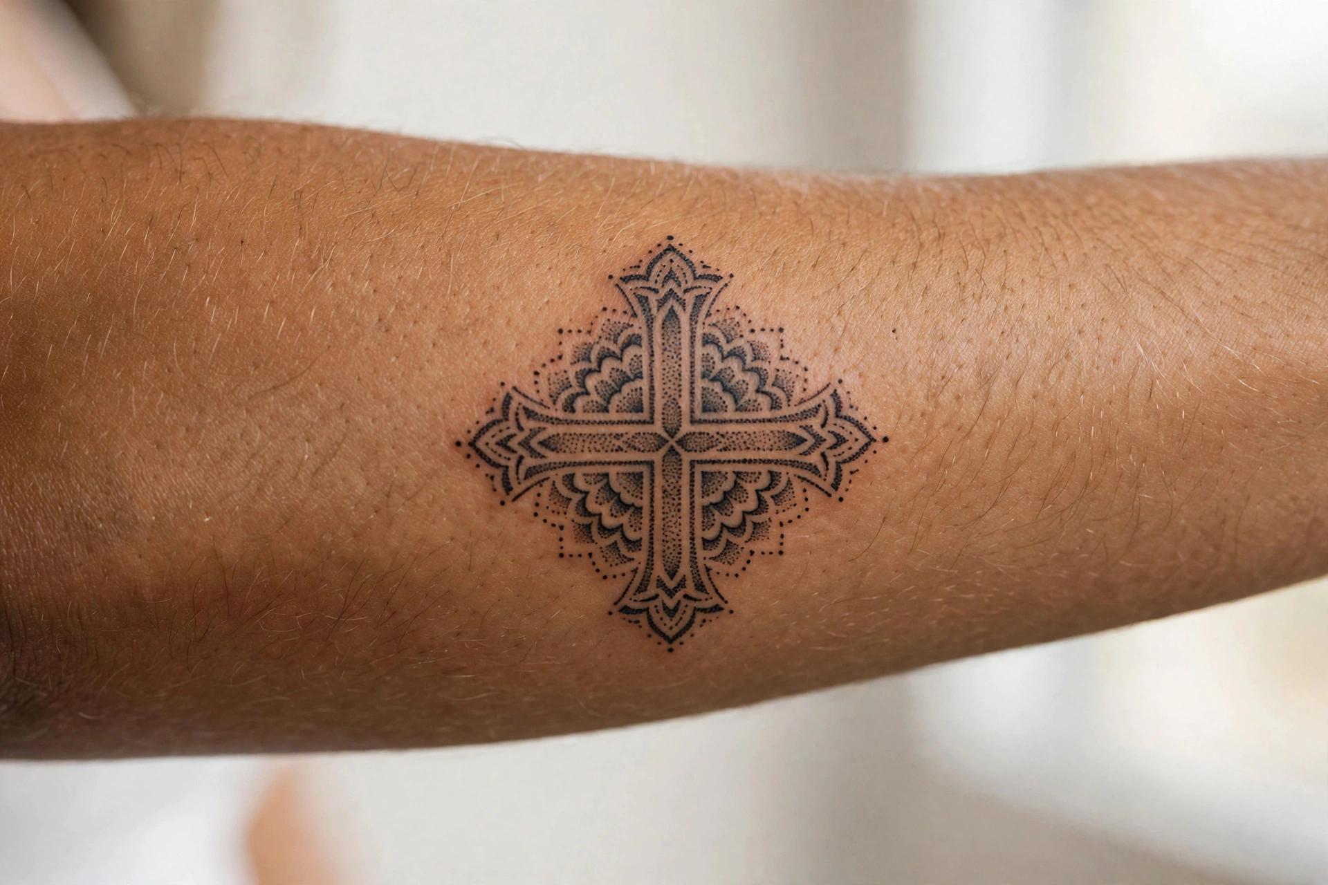Detailed cross tattoo with shading on a man's forearm