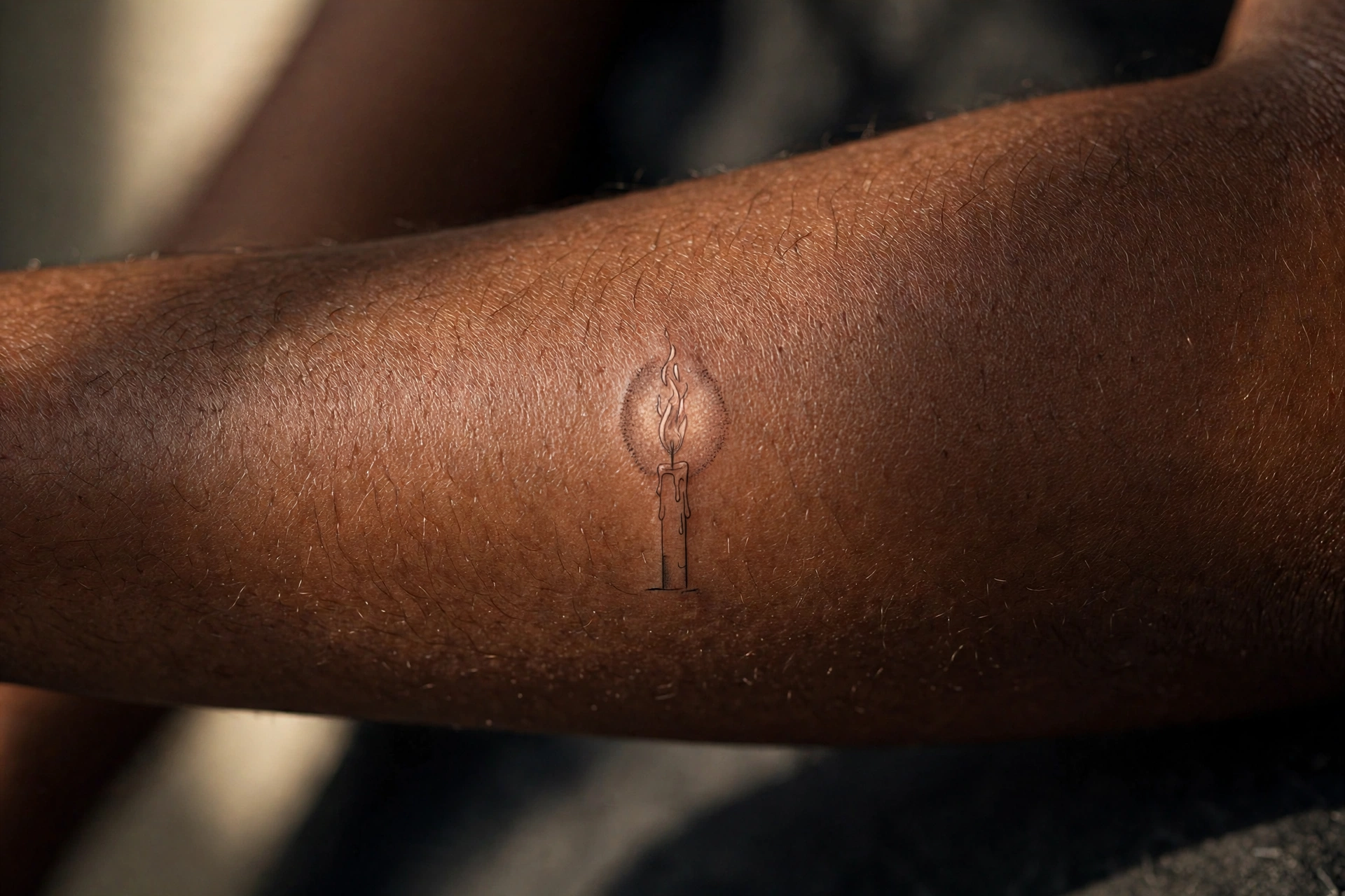 Single candle flame memorial tattoo on the wrist