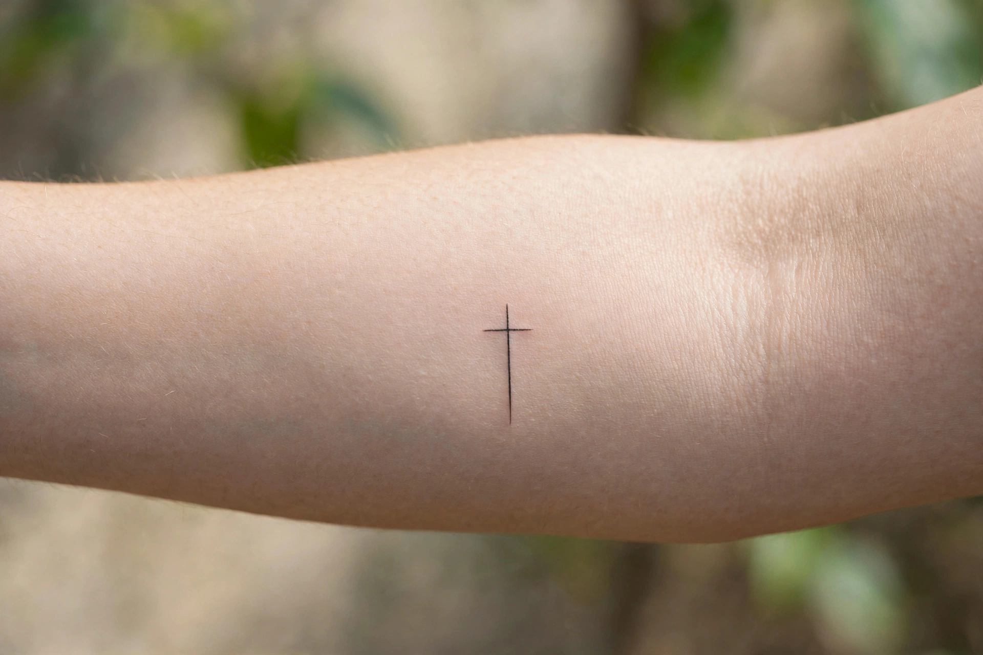 Minimal cross memorial tattoo on the wrist or ankle