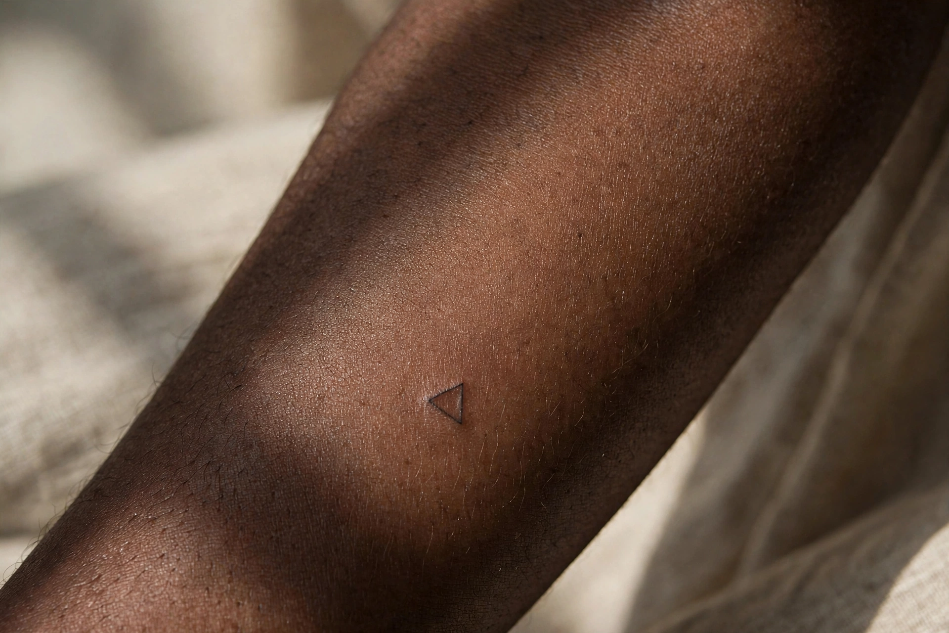 Tiny geometric triangle tattoo on man's wrist