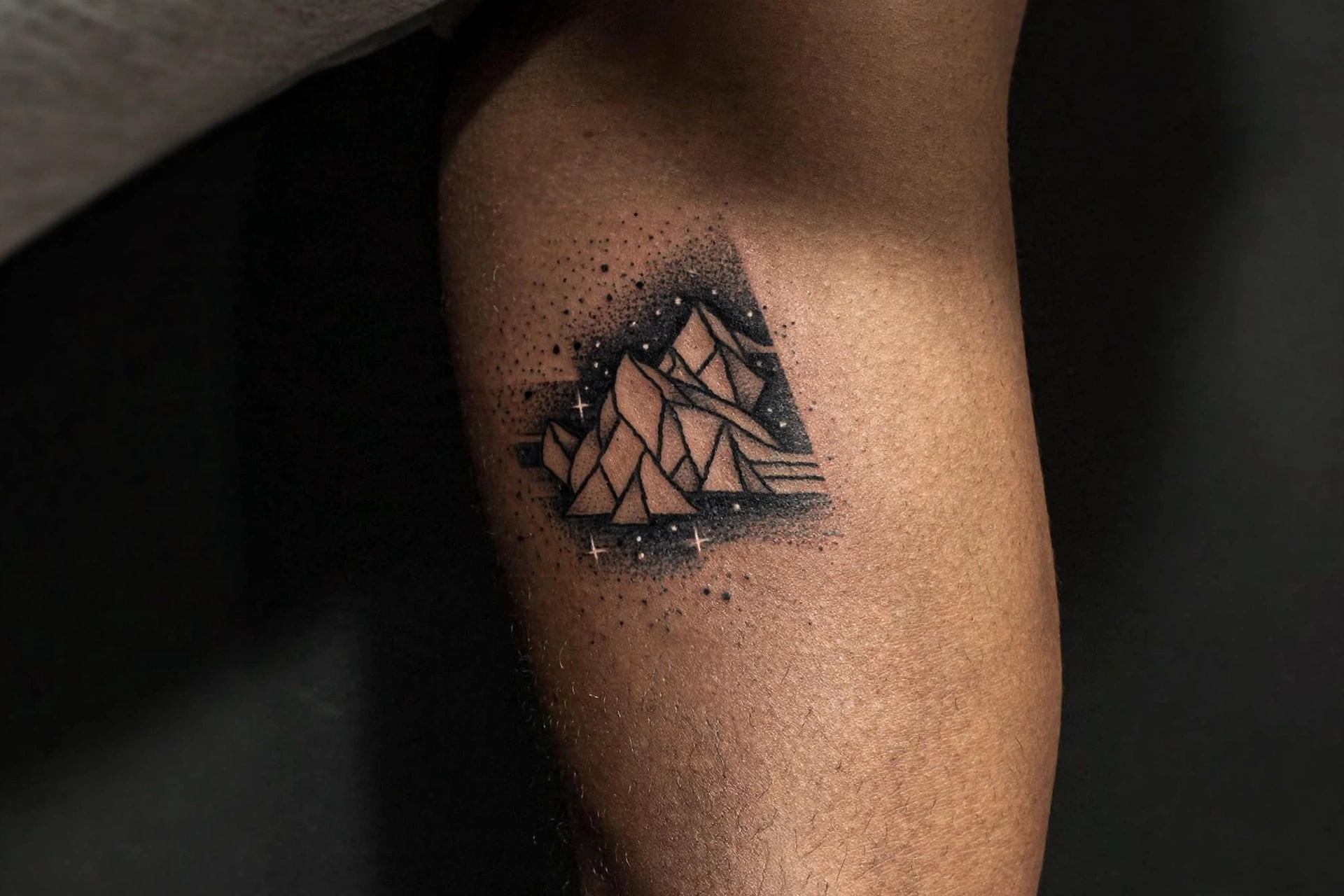 Negative space mountain minimalist tattoo on man's bicep