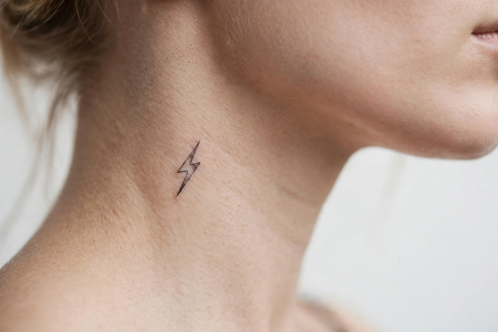 Small lightning bolt tattoo on the side of a neck