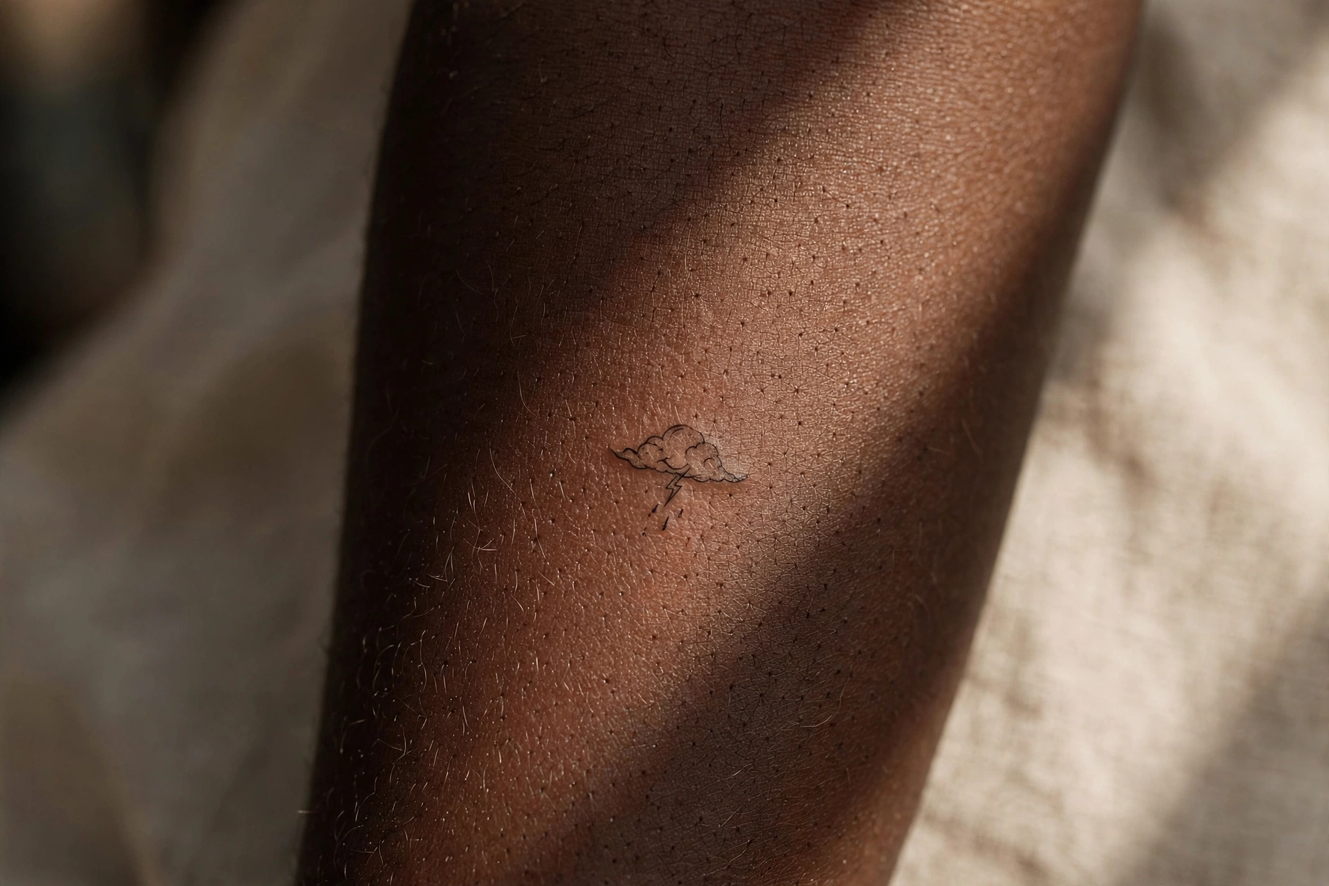 Tiny storm cloud tattoo on man's shoulder