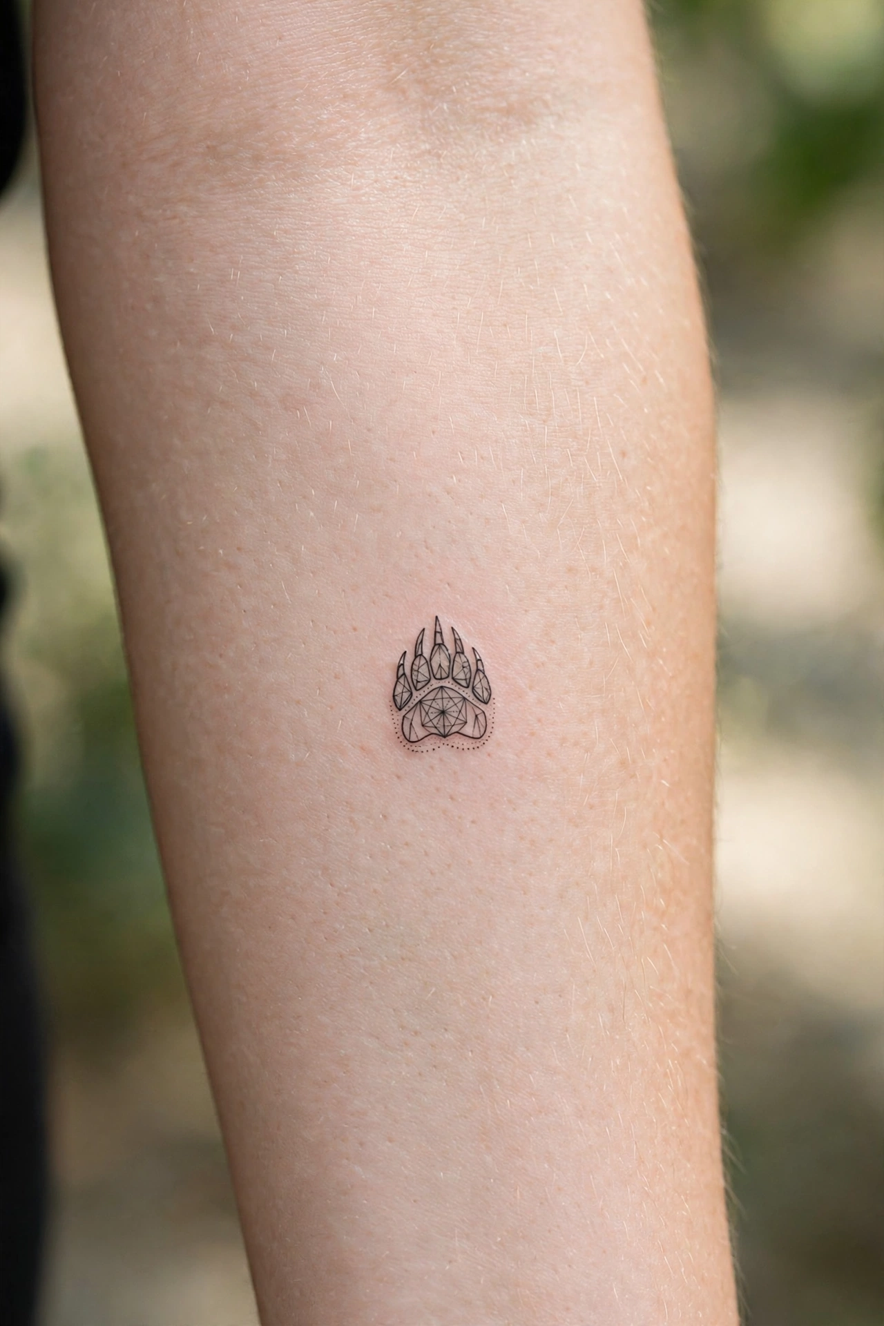 Tiny bear paw tattoo on man's calf