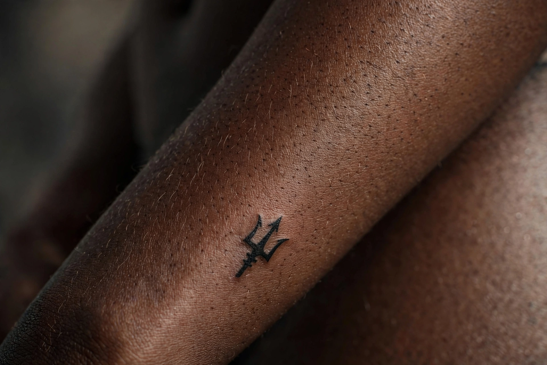 Tiny trident tattoo on man's calf