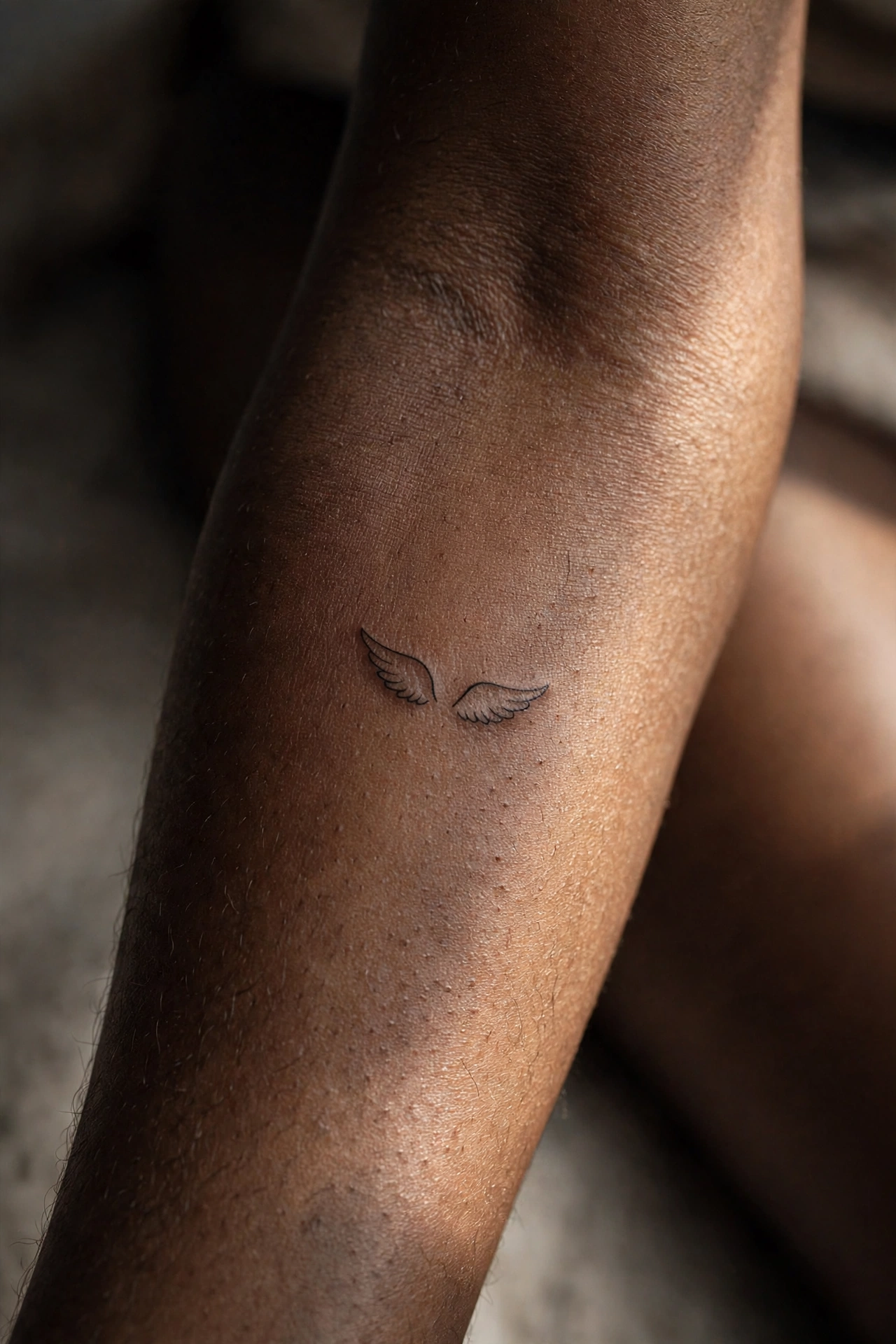 Mini wings tattoo on man's neck