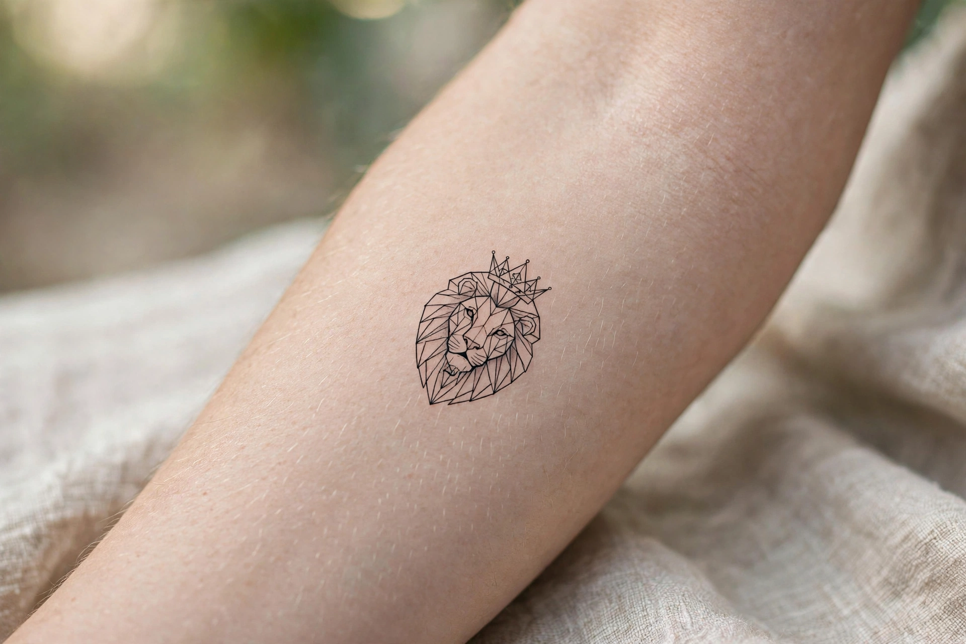 Small crowned lion tattoo on man's forearm
