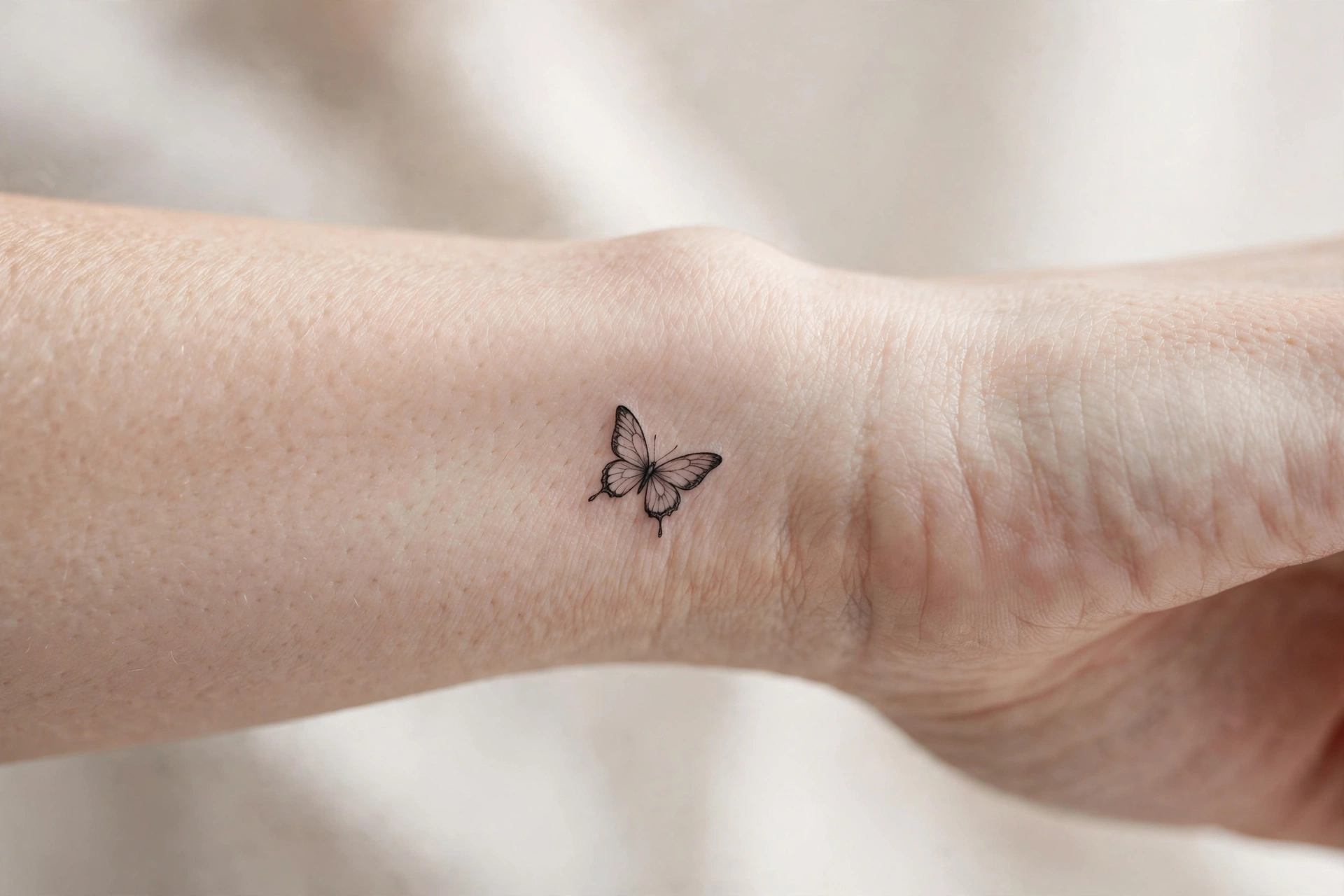 Mini lotus flower tattoo in fine black lines on a wrist